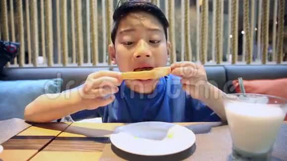 快乐的亚洲男孩微笑着吃面包片视频的预览图