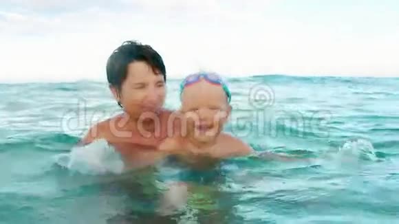 快乐的儿子和母亲微笑着看着镜头在海上缓慢的动作中飞溅视频的预览图