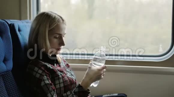 年轻女子乘火车旅行时喝水视频的预览图