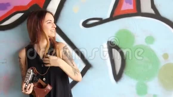 有纹身的女孩站在涂鸦墙和照片附近视频的预览图