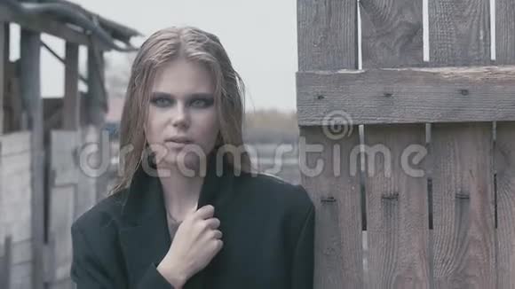 阴天时穿着黑色衣服的漂亮金发女孩在栅栏附近视频的预览图