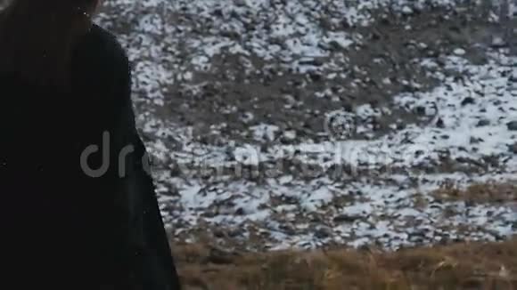 穿着黑色外套的女孩走在白雪覆盖的田野上视频的预览图