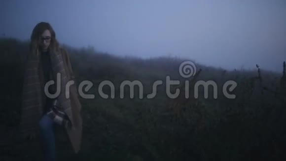 戴眼镜的女孩走在朦胧的山丘上视频的预览图