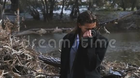 一个穿着黑色外套的被晒黑的女孩在河边冻僵了视频的预览图