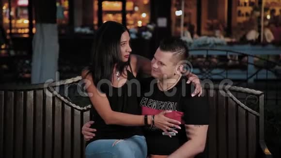 快乐的男人和女人在晚上的长凳上牵手聊天视频的预览图