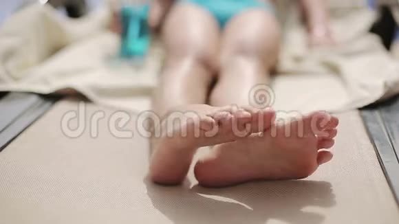 孩子躺在酒店游泳池旁的日光浴卧室上移动她的脚视频的预览图