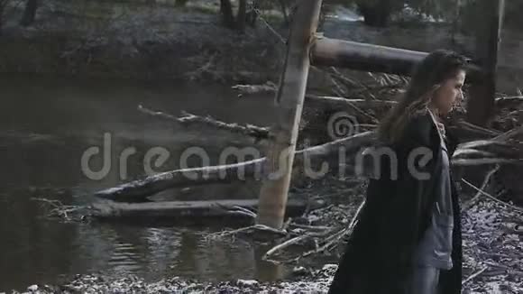 穿着西装的漂亮女孩在河和干树枝的背景下视频的预览图