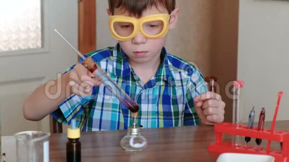 家庭化学实验男孩在燃烧的酒精灯上用红色液体加热试管液体沸腾了视频的预览图