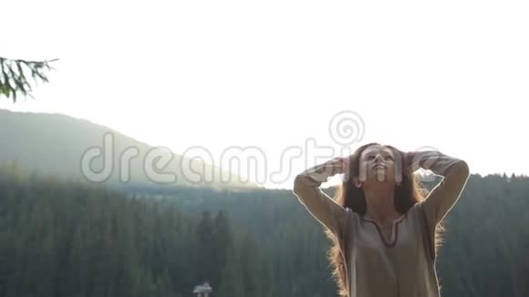 身着乌克兰传统白色夏装的性感黑发女孩站在山谷里摸着头发视频的预览图