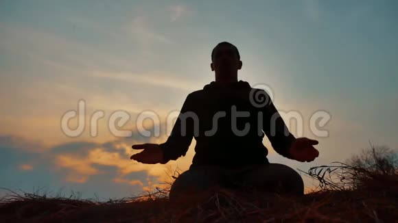 一位在日落阳光下冥想的男僧的剪影佛教祈祷日落健康生活方式视频的预览图