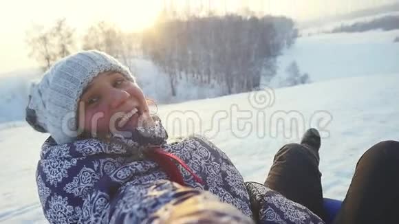 年轻开朗的女人在美丽的夕阳下缓慢地从山上滑过雪地1920x1080视频的预览图