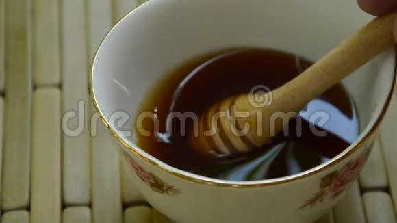 用手从杯子中取出木制蜂蜜勺视频的预览图