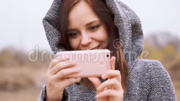 年轻风格的女孩在公园里用手机自拍视频的预览图