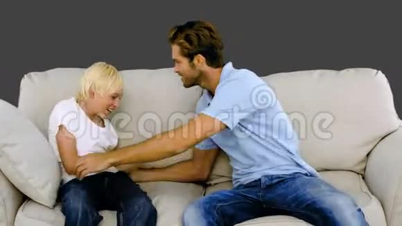 父亲在灰色背景的沙发上挠着儿子视频的预览图