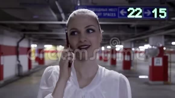 穿着白色衬衫和黑色裙子在地下停车场散步的漂亮女人视频的预览图
