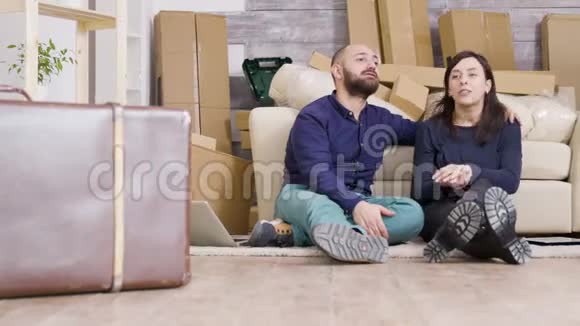 一对白人年轻夫妇坐在新公寓的地板上视频的预览图