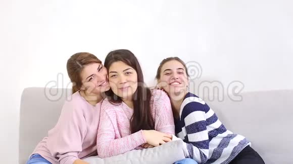 三个迷人的年轻朋友在镜头上微笑着摆姿势坐在明亮的卧室里的沙发上视频的预览图