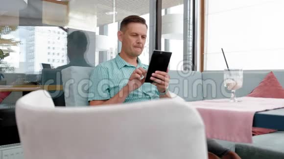 咖啡馆里使用平板电脑触摸屏的成熟男人视频的预览图