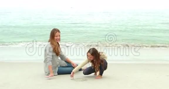 母亲和女儿在沙滩上画画视频的预览图