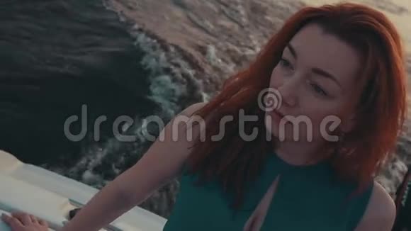 在摩托艇上穿绿松石衣服的红发女孩晚上好抚摸头发视频的预览图