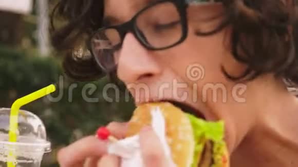 十几岁的男孩在户外咖啡馆吃汉堡包和炸薯条特写视频的预览图