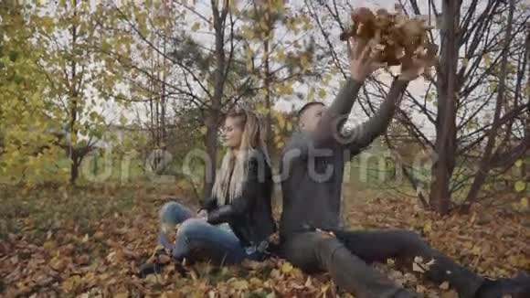 一对年轻的幸福夫妇在秋天的公园里玩和扔树叶视频的预览图