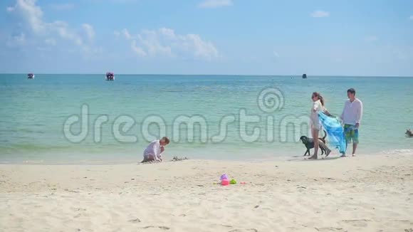 幸福的家庭有孩子和狗在沙滩上散步天气炎热的热带岛屿视频的预览图