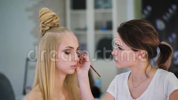 在美容院化妆的性感金发女郎用阴影强调眼睛视频的预览图