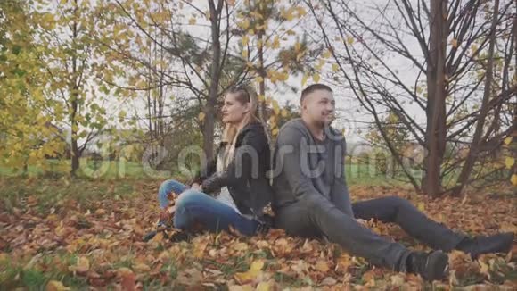 一对年轻的幸福夫妇在秋天的公园里玩和扔树叶视频的预览图