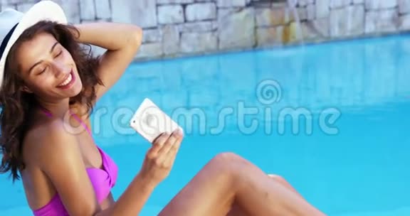 微笑的女人在泳池边拍照视频的预览图