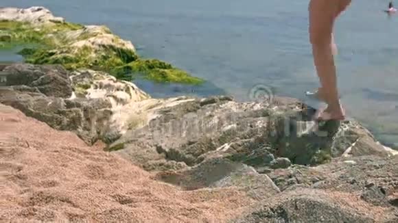 海滩上漂亮的模特女孩靠近大海的天然石头视频的预览图
