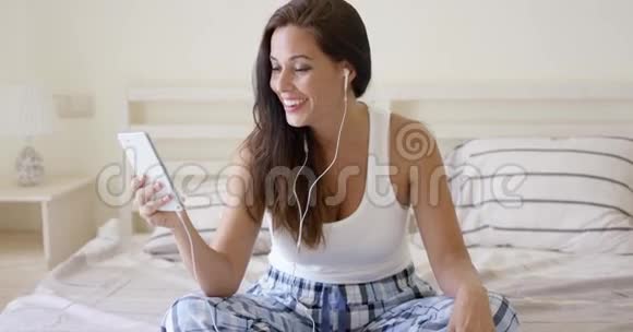 快乐的女人听着耳塞和药片视频的预览图
