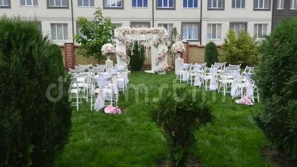 婚礼上一排排椅子婚庆花拱装饰用鲜花装饰的婚礼拱门室外视频的预览图