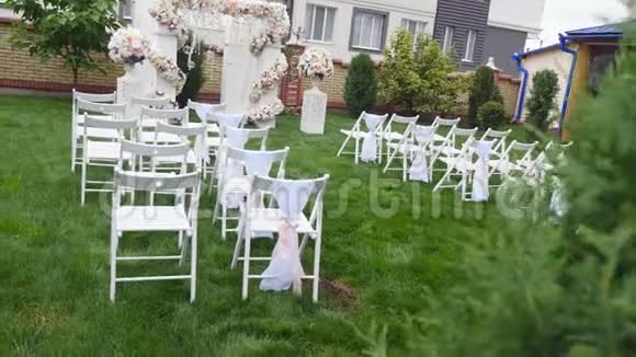 婚礼上一排排椅子婚庆花拱装饰用鲜花装饰的婚礼拱门室外视频的预览图