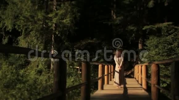 美丽的赤脚女子穿着刺绣的传统长裙走在喀尔巴阡山的木桥上晒太阳视频的预览图