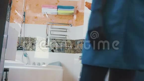 年轻女孩穿着蓝色毛巾走在浴室打开水龙头触摸水视频的预览图