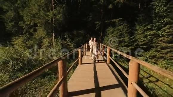 浪漫的情侣在喀尔巴阡山的木桥上穿着传统刺绣的衣服幸福地走着视频的预览图