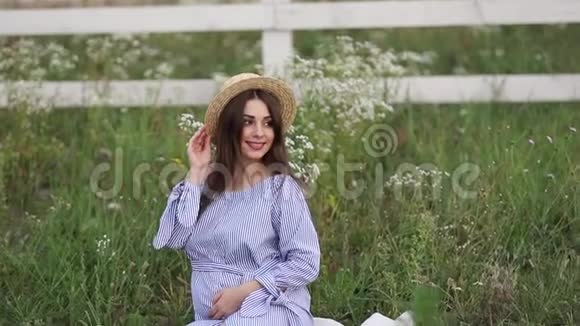 年轻孕妇坐在田里放松她拿了一个水果篮夏季视频的预览图