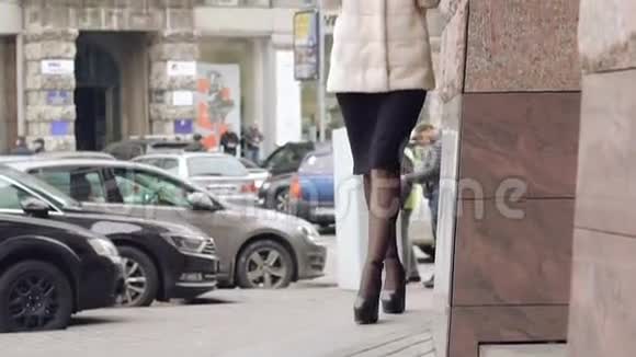 穿着毛茸茸外套的时髦女人走在街上的跑道上慢慢地视频的预览图