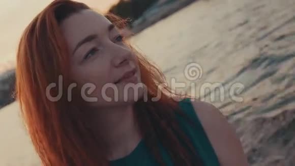 年轻的红发女孩穿着绿松石的裙子坐在帆船上日落幸福快乐视频的预览图