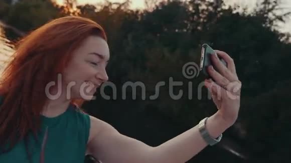 幸福的红发女孩穿着绿松石衣服在帆船上自拍日落视频的预览图