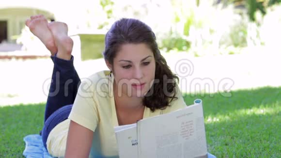 少女躺在草地上阅读杂志视频的预览图