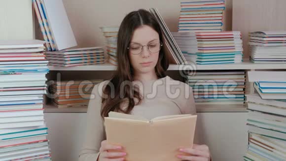 年轻的黑发女人戴着眼镜看书坐在书中视频的预览图