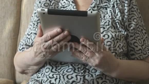 一位老妇人用数码平板电脑看照片视频的预览图