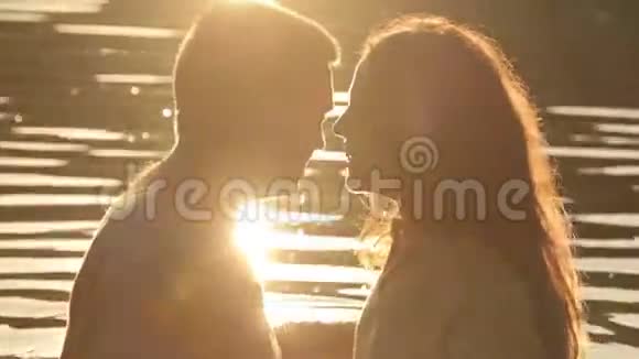 两个情人在晚上的背景下在湖边接吻的剪影宁静的浪漫时刻视频的预览图