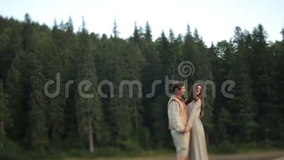 喀尔巴阡山森林里一对美丽的年轻夫妇穿着传统的乌克兰服装拥抱在一起视频的预览图
