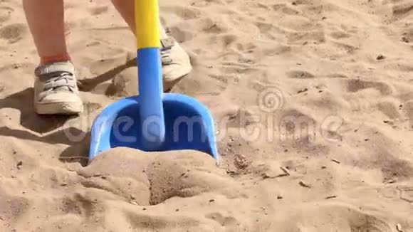 玩具铲子和小男孩的脚在夏天沙子上视频的预览图