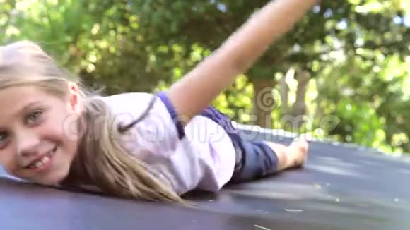 少女躺在花园里的蹦床上视频的预览图