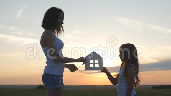 剪影幸福的母女和梦想的房子纸房子作为象征家庭幸福的概念视频的预览图