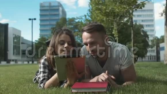 年轻的浪漫夫妇在公园里玩平板电脑视频的预览图